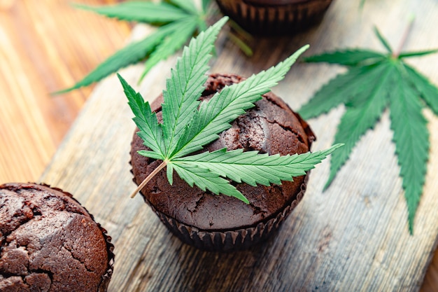 Magdalenas de chocolate con cbd de marihuana. Drogas de cáñamo de marihuana medicinal en postre alimenticio, legalización de ganja. Cocinar magdalenas de chocolate para hornear. Magdalena con marihuana. Vista superior.