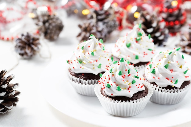 Magdalenas de chocolate decorado crema blanca y abetos en un plato blanco. Dulces navideños. Postre de año nuevo