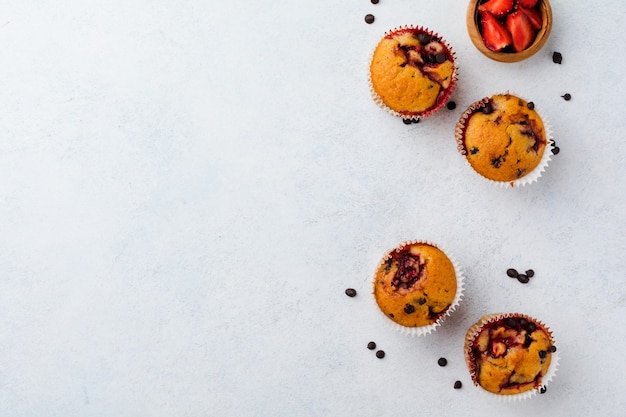 Magdalenas de chocolate con fresa muffins sobre superficie blanca de hormigón