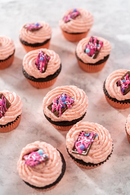 Foto magdalenas de chocolate y fresas recién horneadas adornadas con mini chocolates rosados gourmet.