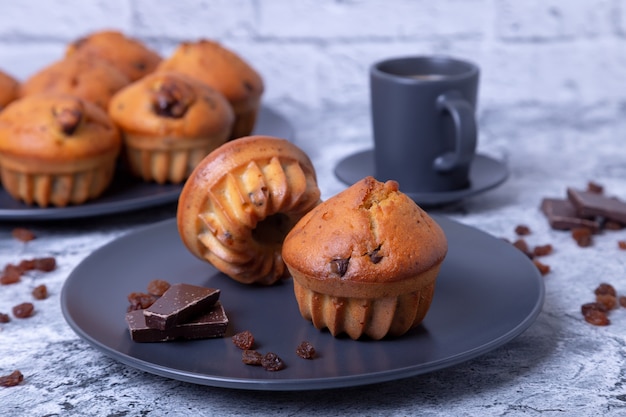 Magdalenas con chocolate y pasas. Horneado casero. Un plato con magdalenas y una taza de café. De cerca.