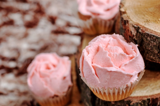 Magdalenas con crema rosa sobre fondo de madera.