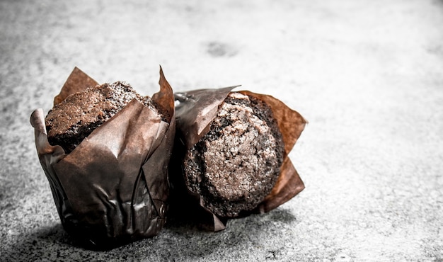 Magdalenas frescas de chocolate en la mesa rústica.