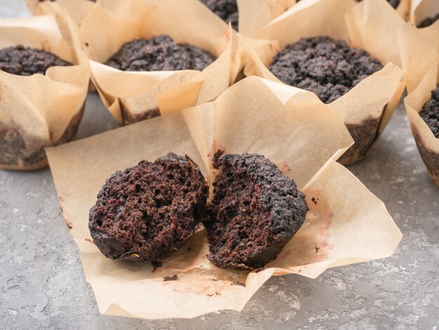 Magdalenas veganas de chocolate sin gluten con remolacha, polvo de almendras, harina de trigo sarraceno y karob o cacao. Magdalenas caseras sobre fondo de hormigón gris con copyspace