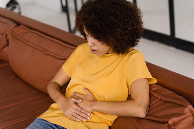 Foto magenschmerzen krankes afroamerikanisches mädchen hält bauch, weil es schmerzt pankreatitis-krankheit der bauchspeicheldrüse entzündet sich