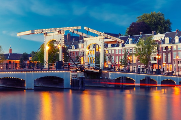 Magere Brug, Skinny Bridge, mit Nachtbeleuchtung über den Fluss Amstel im Stadtzentrum von Amsterdam, Holland, Niederlande. Gebrauchte Tonisierung