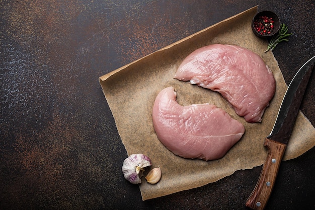 Mageres rohes Putenfilet auf Backpapier mit Rosmarin-Knoblauch