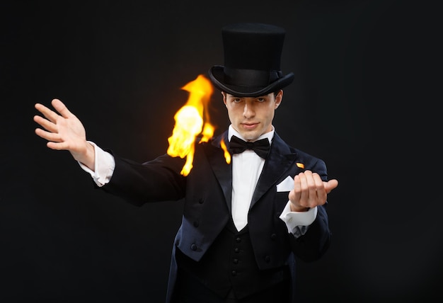 Magia, actuación, circo, concepto de espectáculo - mago con sombrero de copa mostrando truco con fuego