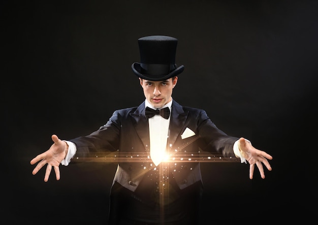 Magia, performance, circo, concepto de espectáculo - mago con sombrero de copa mostrando truco