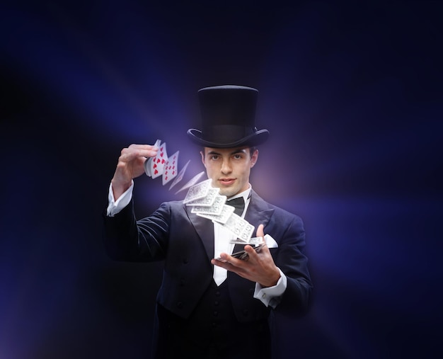 Foto magia, performance, circo, juegos de azar, casino, póquer, concepto de espectáculo - mago con sombrero de copa mostrando truco con naipes