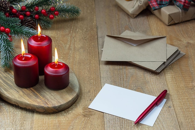 Foto magic christmas tres velas encendidas rojas junto a una carta, un árbol de navidad y regalos