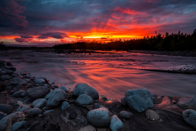 Mágica puesta de sol ardiente sobre un hermoso lago con una costa rocosa