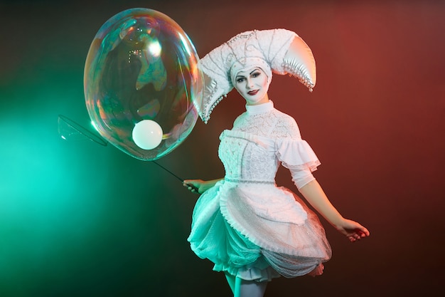 Mágico de artista de circo mostra truques com bolhas de sabão. Uma mulher e uma garota inflam bolhas de sabão