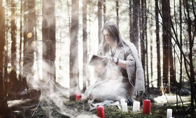 Mágico de fada. Um feiticeiro com uma esfera de vidro, um feitiço mágico e um ritual. Ancião com um bastão e uma cruz na floresta. Magia preta e branca. Um feitiço em um livro antigo.