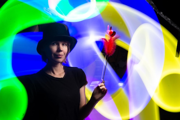 Mágico de mulher de chapéu preto contra um fundo de luz multicolorida Conceito de horóscopo mágico de feitiçaria