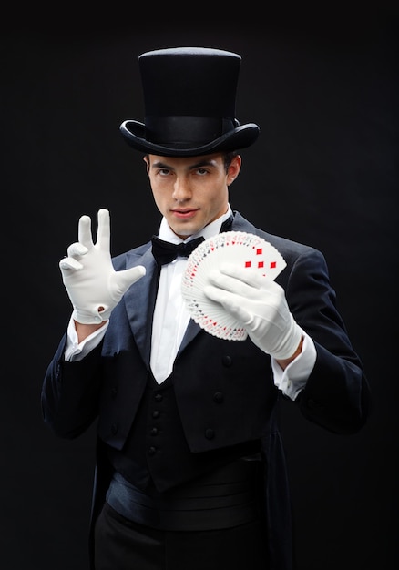 Magie, Performance, Zirkus, Glücksspiel, Casino, Poker, Showkonzept - Zauberer im Zylinder zeigt Trick mit Spielkarten