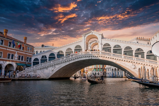 Magische Aussicht auf die traditionelle Gondel in der Nähe des weltberühmten Canal Grande und der Rialtobrücke bei Sonnenuntergang in Venedig, Italien. Retro-Vintage-Instagram-Filter und Flare-Effekt hinzugefügt.