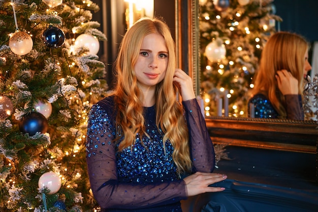 Magische Weihnachtsnacht schöne Frau in einem blauen Abendkleid feiert Weihnachten in einem luxuriösen S...