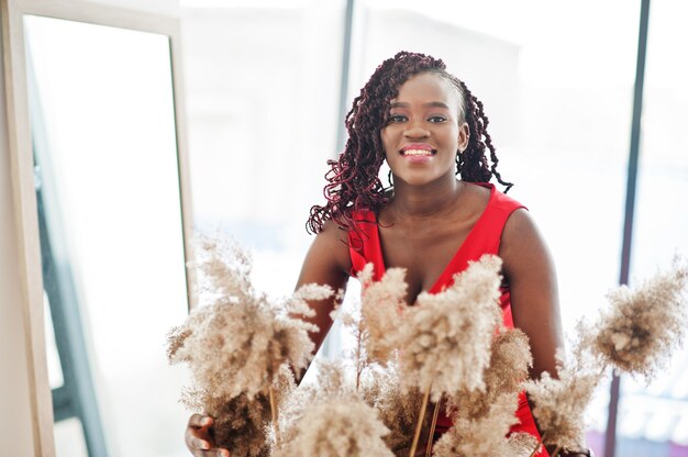 Magnífica jovem africana em um luxuoso vestido vermelho em um apartamento de luxo. Beleza, moda.