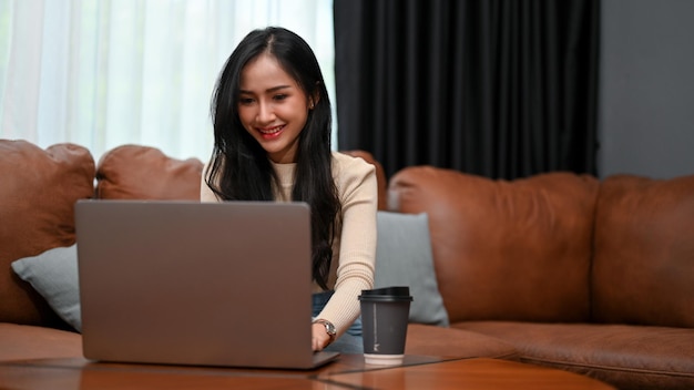 Magnífica mujer independiente asiática o mujer de negocios que trabaja desde casa usando una computadora portátil