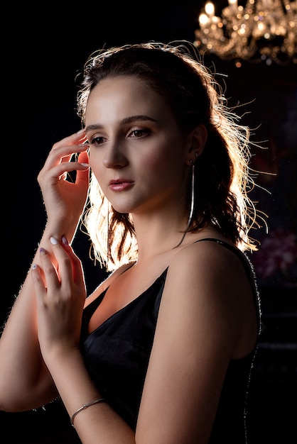 Magnífica mulher morena posando em uma sala com sombras no fundo do lustre