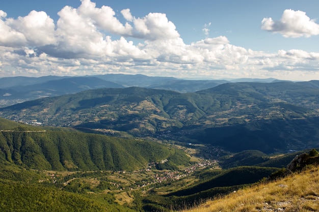 Magnífica vista panorámica de un vasto paisaje con colinas verdes bajo un cielo brillante lleno de nubes blancas