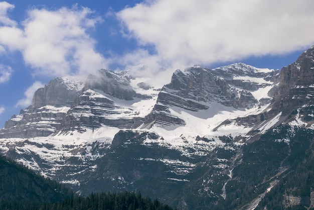 Magníficamente visibles capas de rocas montañosas de picos alpinos cubiertos de nieve. Ciudad de Anaunia, Italia