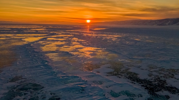 Magnífico pôr do sol sobre o lago congelado Baikal Pedaços de gelo congelados na superfície do lago Rússia