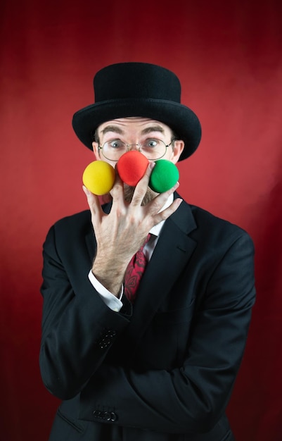 Mago caucásico vintage con gafas de sombrero de copa y bigote con bolas de colores con fondo rojo