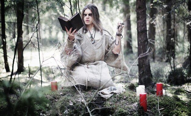 Mago de hadas. Un hechicero con una esfera de cristal, un hechizo mágico y un ritual. Anciano con un bastón y una cruz en el bosque. Magia en blanco y negro. Un hechizo en un libro antiguo.