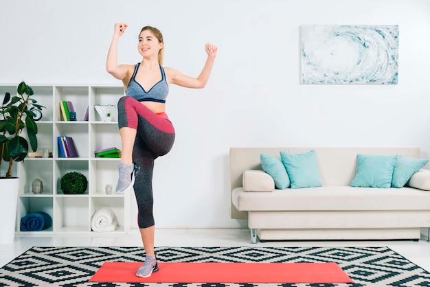 Magro feminino em activewear fazendo exercício na sala de estar