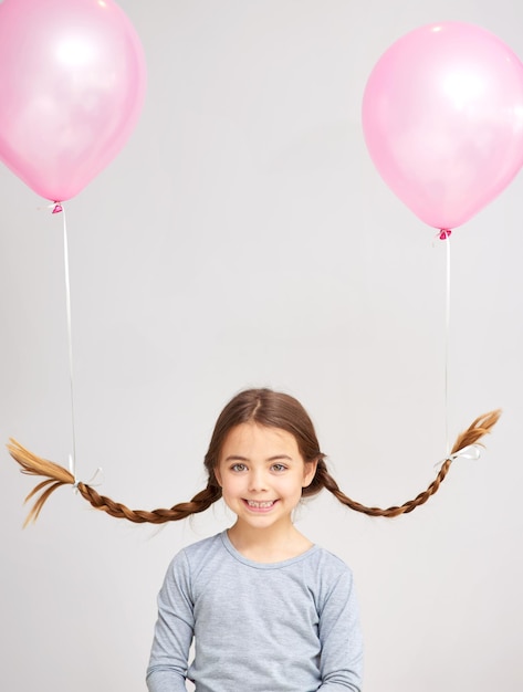 Magst du meine Frisur Studioporträt eines süßen kleinen Mädchens mit Luftballons an ihren Zöpfen