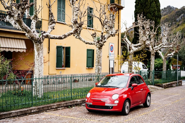 Mailand Italien Juli ein rotes Fiat Auto geparkt vor einem Haus mit Platanen oder Chinar im Garten