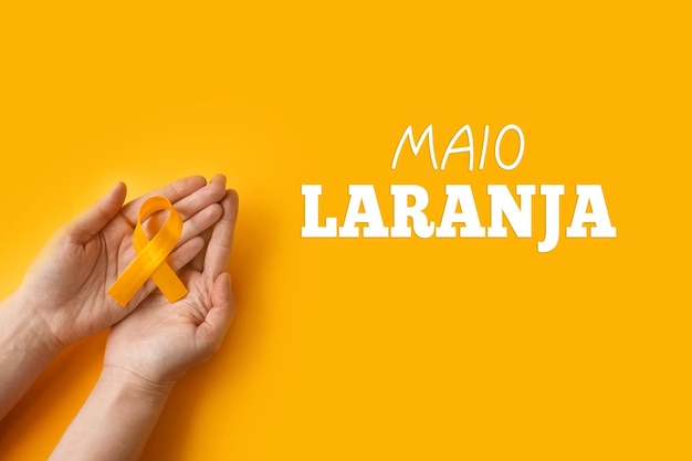 Maio laranja Mãos segurando uma fita laranja Proteção de crianças e adolescentes contra a violência
