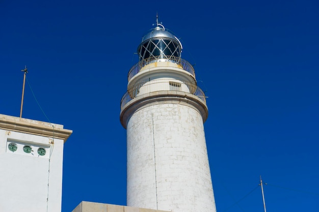 Maiorca, farol junto ao Mar Mediterrâneo, céu azul sem nuvens com águas calmas. serve para avisar os navios da presença de rochas