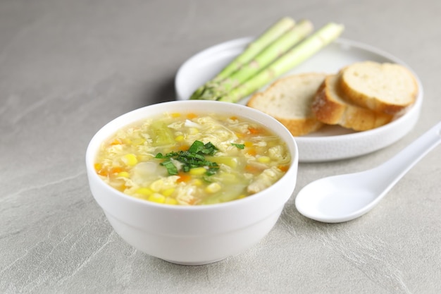 Mais-Spargel mit Eiertropfensuppe in weißer Schale und knusprigem Brot