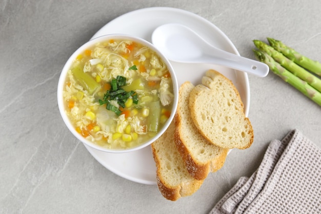 Mais-Spargel mit Eiertropfensuppe in weißer Schale und knusprigem Brot