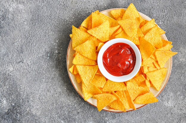 Maischips mit Ketchup in einem Teller auf grauem Hintergrund Draufsicht