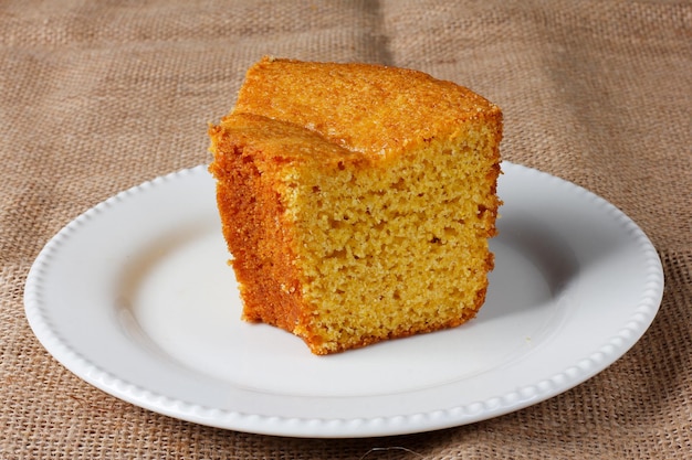 Maiskuchen auf einem weißen Teller auf einem rustikalen Holztisch Typische brasilianische Partygerichte