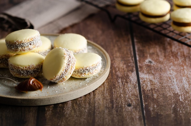 Maisstärke Alfajores mit Milchkaramell und Kokosnuss auf einem Teller und auf einem schwarzen Gestell