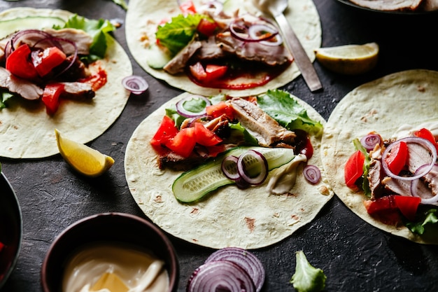 Maistortillas gefüllt mit Hühnchen und Gemüse auf einem Holztisch Tacos kochen