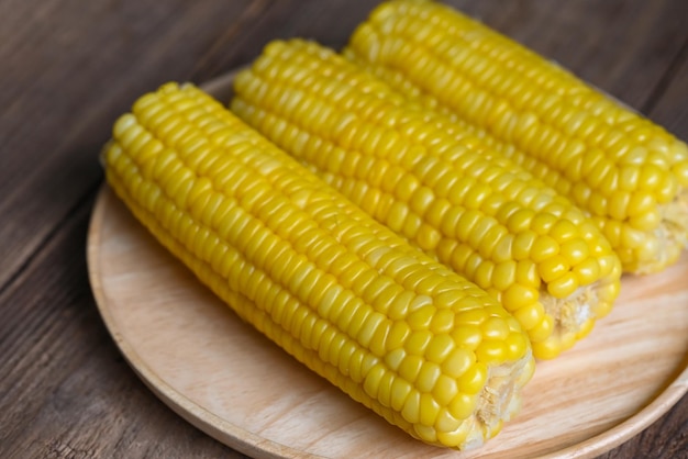 Maíz dulce cocido sobre fondo de placa de madera mazorcas de maíz maduras al vapor o maíz dulce hervido para comida vegana cena o merienda