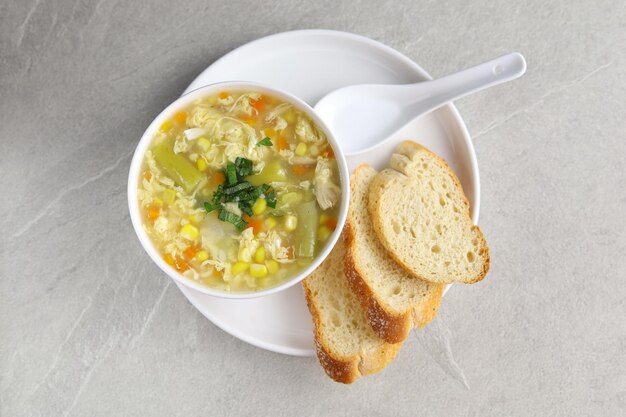 Maíz y espárragos con sopa de huevo en tazón blanco y pan crujiente