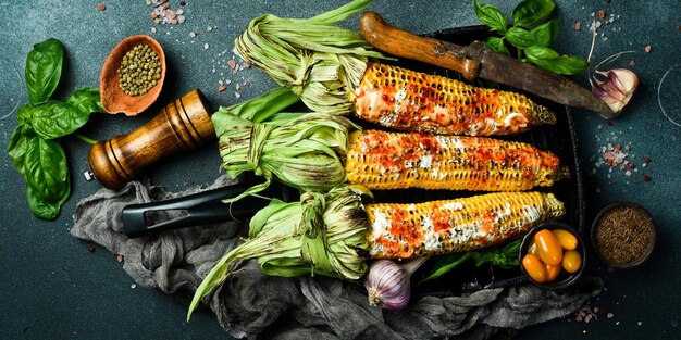 Foto maíz a la parrilla con especias y salsas sobre un fondo de piedra negra barbacoa comida orgánica vista superior