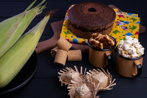 Maíz verde y dulces de festa junina en mesa de madera negra