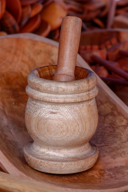 Maja de madera en tinte rojizo en medio de varios utensilios de cocina artesanales