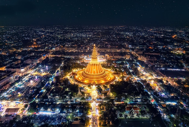 Majestoso pagode dourado de Phra Pathom Chedi brilhando entre as luzes do festival ao redor da rotatória no centro de Nakhon Pathom