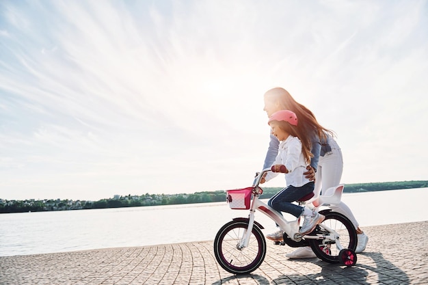 Majestuosa vista del lago Madre con su hija pequeña está con bicicleta al aire libre juntos
