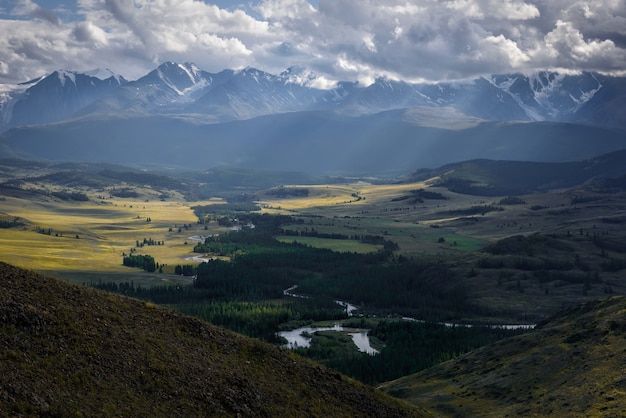 Majestuoso paisaje. Nubes de lluvia picos nevados con rayos de sol. Tormenta azota la estepa de Kurai en Altai