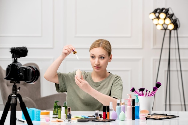 Make-up-Blogger erstellt Make-up-Tutorial vor der Kamera, junges süßes hübsches Mädchen, das Serum einsetzt